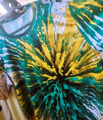 A imagem mostra uma camiseta impressa em sublimação, com uma explosão de tintas verde e amarelo