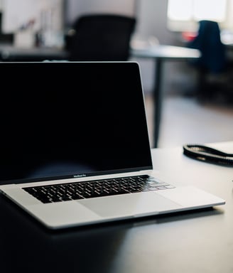a laptop computer sitting on a desk with a phone and a telephone