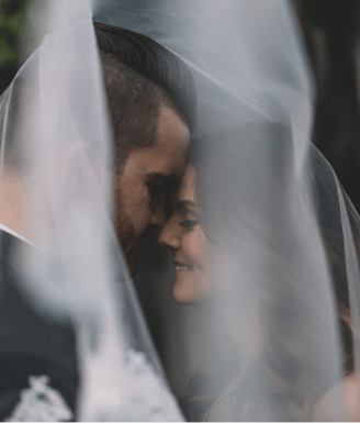 a bride and groom are standing in front of a veil