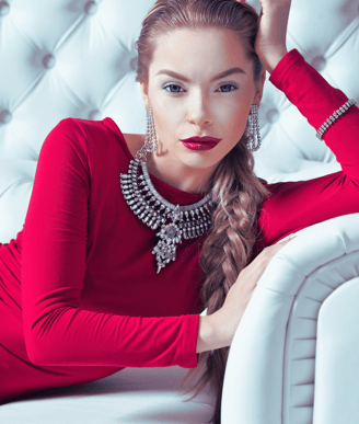 Elegant empowered woman in red dress on a white couch, symbolizing the CEO Metal Archetype in Phoenix Ignited Brand