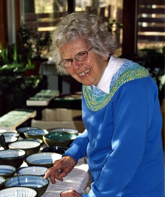 One of our founders, Naoma Powell, pictured with a table full of bowls she made.