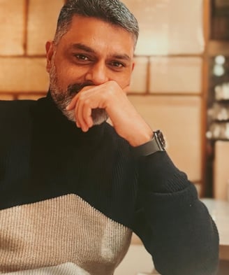 Author and Poet Himayath Khan sitting on a couch smiling