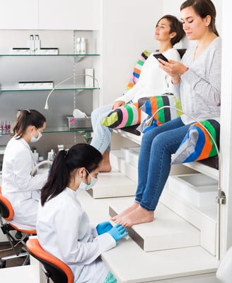 Two lady customers recieving pedicure services