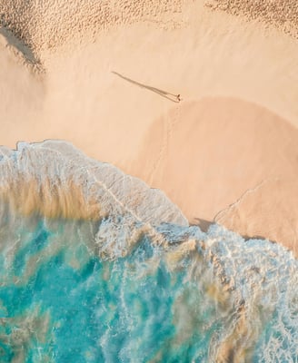 une personne debout sur une plage avec une planche de surf 