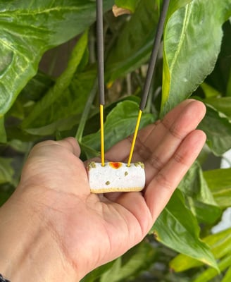 person holding an indian sweet-dish shaped incense holder made of polymer clay in a park