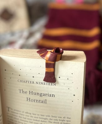 red and yellow gryffindor scarf bookmark made of clay kept on a harry potter book