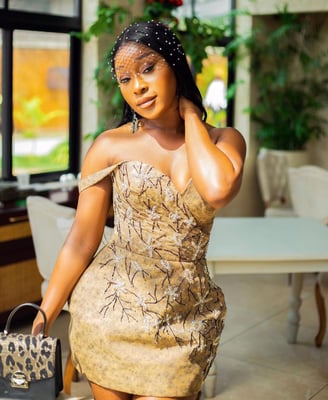 Efia Odo in a stunning brown striped dress with a leopard skinned bag.