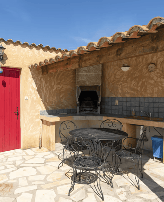 a patio with a table and chairs and a red door