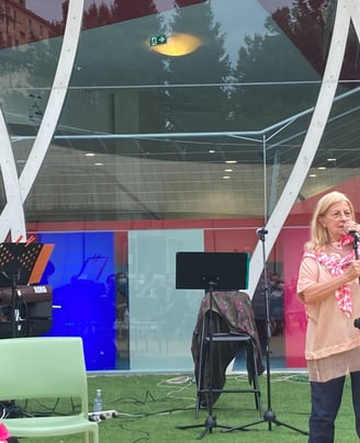 a woman in a pink shirt is standing in front of a microphone and a man