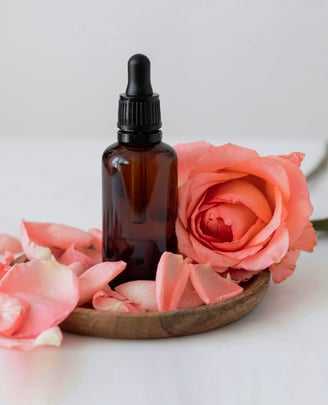 un flacon d'huiles essentielles avec une rose sur un bol en bois