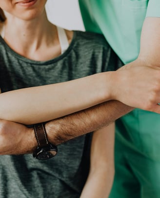 Man supporting woman's arm in treatment.