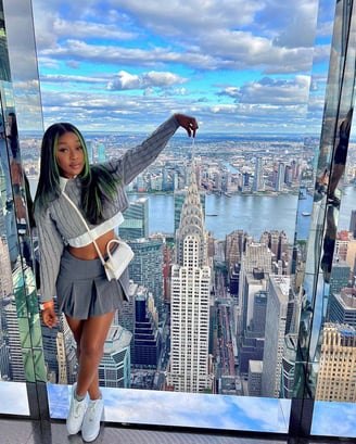 Efia Odo in a gray striped shirt and gray skirt posed behind New York City.