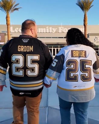 a man and woman holding hands and wearing matching hockey jerseys