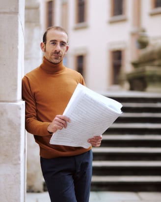 Leonardo Rizzo in a turtle neck sweater holding a piece of paper