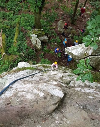 a group of people climbing up a mountain with ropes