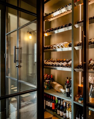 Contemporary wine cellar at Villa La Gratitud with glass doors, backlit shelves, and wine collection