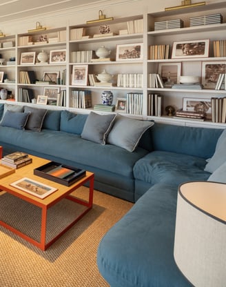 TV lounge at Villa La Gratitud with blue sectional sofa, wall of bookshelves, and large windows.