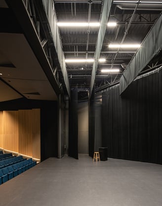 a large empty auditorium with blue seats and a wooden floor