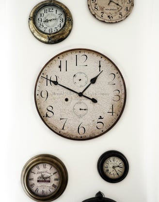 plusieurs vieilles horloges accrochées sur un mur et donnant des heures différenes. Unsplash.