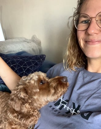 a woman in glasses and a blue shirt is holding a dog