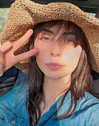 a woman in a straw hat with a straw hat on doing peace sign