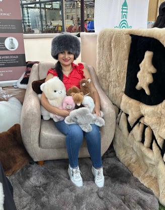 A woman sitting in a chair with alpaca plushies at the APAVIT International Tourism Fair