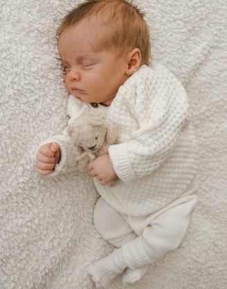 a baby is sleeping on a blanket and holding a teddy bear