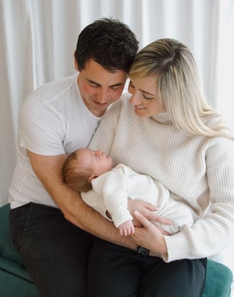 a man and woman holding a baby in a living room