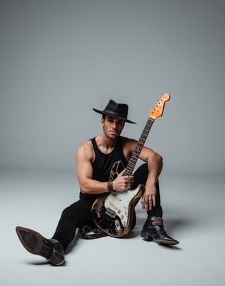 a vocalist in a hat with a guitar