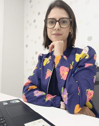 a woman in glasses and a blue jacket sitting at a desk