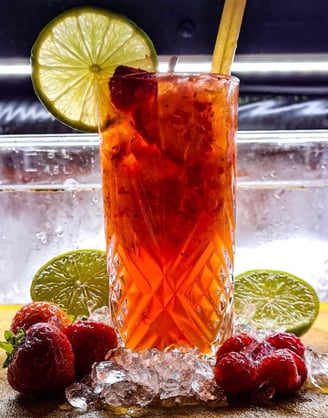 a glass of fruit juice with strawberries and lime