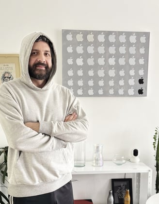 foto do duh vestindo um moleton cinza claro com capuz e uma calça preta, ao lado de seu quadro obsolescência programada .