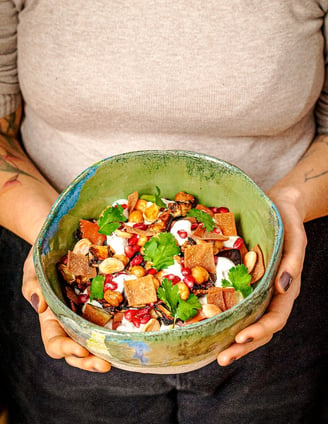 a woman holding a bowl of Lebanese food