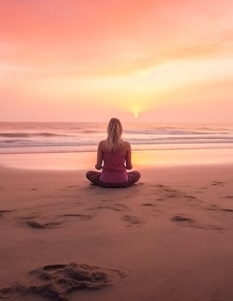 a woman sitting on a beach with a sunset in the background