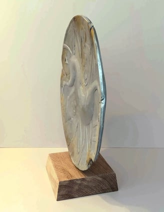 A round plate-like sculpture depicting a stylised horse, painted in blue greys, on oak plinth.