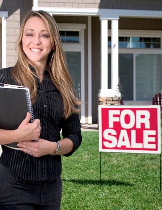 A happy Realtor standing in front of a home she just listed for sale