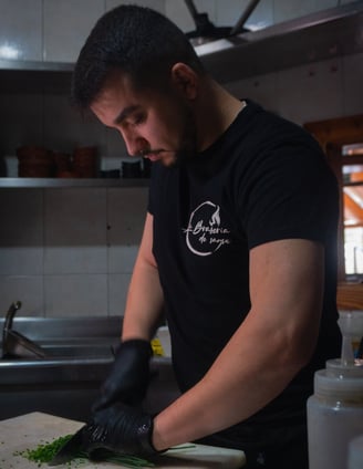 a man in a black shirt is cutting up some vegetables