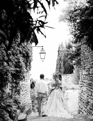 Black and white photo of couple walking hand in hand — cobblestone alley in a Provençal village