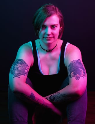 a woman with cat tattoos on her both arms with pink lighting on her skin
