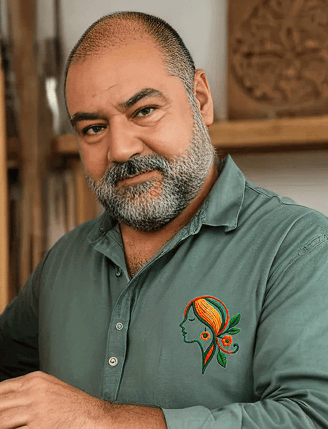 Artesano de Aretística sostiene un cuadro de madera tallado a mano en su taller, mostrando el proces