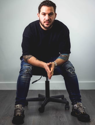 a man sitting on a chair with his hands on his knees