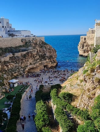 "Polignano a Mare Beach, Puglia – A breathtaking cove surrounded by dramatic limestone cliffs, with 