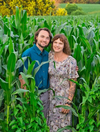 a man and woman standing in a corn field