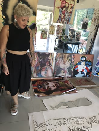 Amanda Amorim aplica spray em uma tela, criando uma obra com temas indígenas.