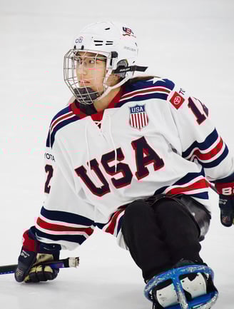 a sled hockey player in a white USA jersey and a hockey helmet