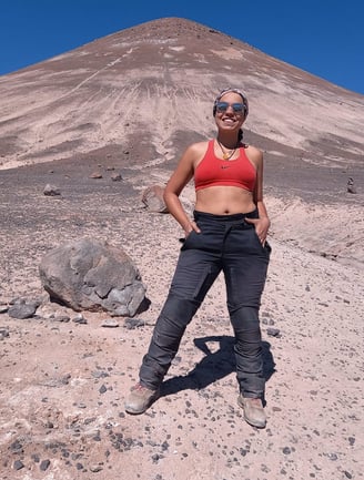 a woman in a red bra top standing in the desert cono de arita puna atacama salar salta