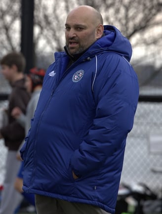a man in a blue jacket coaching rugby