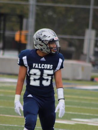 Picture of Isaac in a navy blue football jersey that reads "FALCONS" with the number 25.