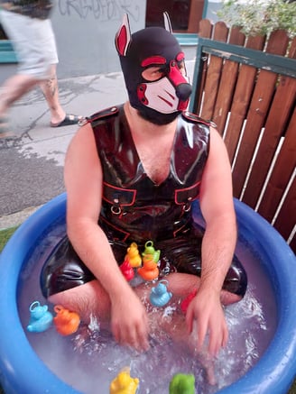 A man playing in a kiddie pool wearing a pup mask.