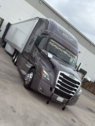a freightliner with a dry van trailer backed into a dock getting unloaded